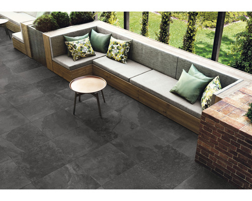 Espace extérieur avec carrelage de sol gris, coin salon avec coussins et petite table