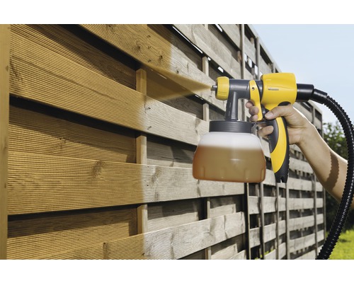 Pulvérisateur de peinture en utilisation sur une clôture en bois