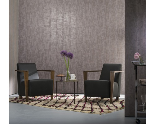 Deux fauteuils et une table sur un tapis à motifs devant un mur texturé