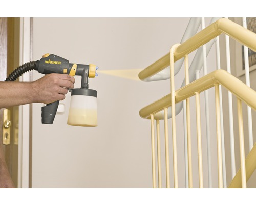 Une personne peint une rampe d''escalier avec un système de pulvérisation de peinture.