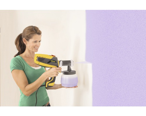 Frau verwendet Farbsprühsystem von Wagner zum Streichen einer Wand