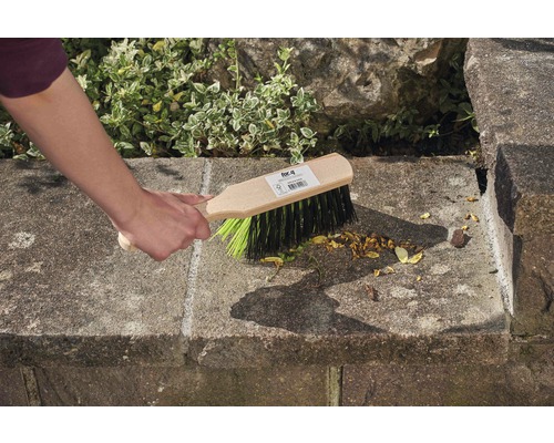 Une main balaie un escalier en pierre avec une brosse de balayage