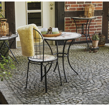 Gartenszene mit Mosaiktisch, Stuhl mit Fellauflage und Dekoration im Aussenbereich