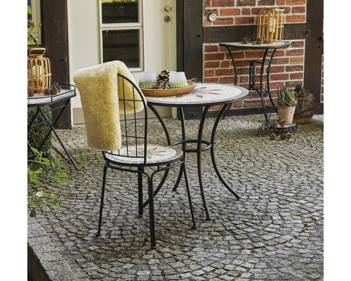 Gartenszene mit Mosaiktisch, Stuhl mit Fellauflage und Dekoration im Aussenbereich
