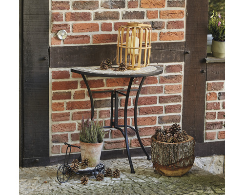 Scène décorative avec table, lanterne, plantes et pommes de pin devant un mur de briques