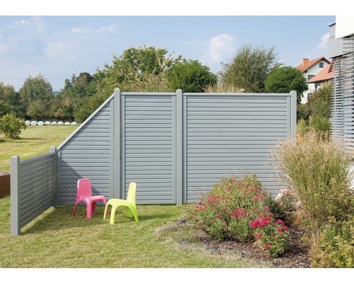Vue de jardin avec un écran de protection visuelle gris et deux chaises d''enfant sur une pelouse