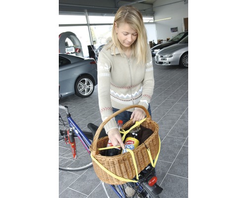 Frau befestigt Fahrradkorb am Fahrrad für den Transport