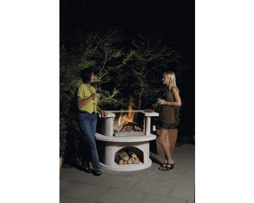 Deux femmes se tiennent à côté d''un barbecue en pierre avec du bois et du feu.