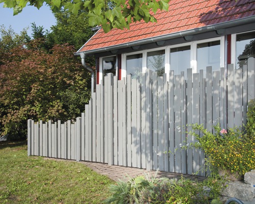 Clôture en bois avec bord supérieur irrégulier devant une maison