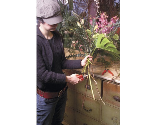 Femme coupant des fleurs avec un sécateur pour une composition florale
