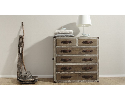 Kommode mit Schubladen, Tischlampe und Dekoration in einem Zimmer