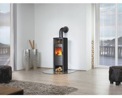 Poêle à bois avec plaque de sol en verre dans un salon lumineux avec de grandes fenêtres.