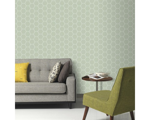 Wohnzimmer mit grauer Couch, grünem Stuhl und Wandtapete mit geometrischem Sechseckmuster