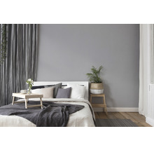Chambre claire avec lit, coussins, couverture, rideaux et plantes