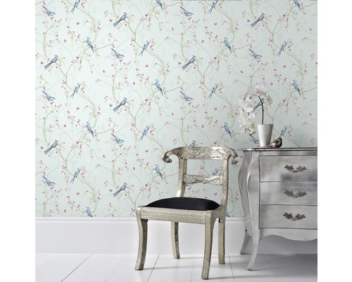 Raum mit Vogelmuster-Tapete, silbernem Stuhl und Kommode