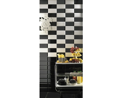 Décoration murale avec motif en damier réalisée avec des carreaux noirs et blancs, complétée par un chariot de service et des éléments de décoration.