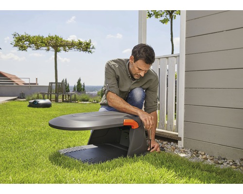 Un homme installe un robot de tonte dans le jardin