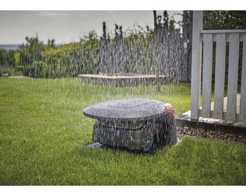 Robot tondeuse à gazon en marche sous la pluie sur une pelouse.