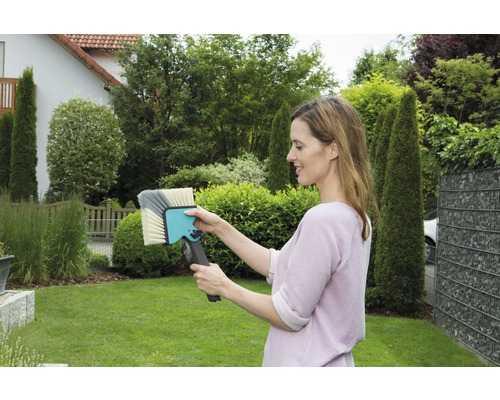 Frau hält eine Waschbürste im Garten