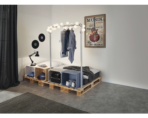 Chambre avec lit en palettes de bois, décorée avec une guirlande lumineuse et un poster de musique