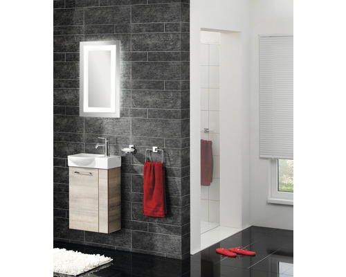 Modernes Badezimmer mit Waschtisch, beleuchtetem Spiegel, dunklen Fliesen und Dusche.