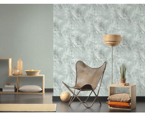 Salon avec papier peint à motifs, étagère en bois et fauteuil en cuir