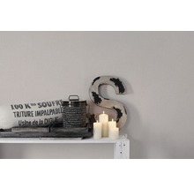 Scène décorative avec coussin, boîte, bougies et lettre décorative sur une étagère