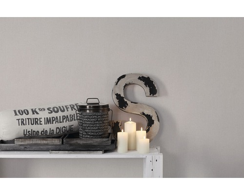 Scène décorative avec coussin, boîte, bougies et lettre décorative sur une étagère