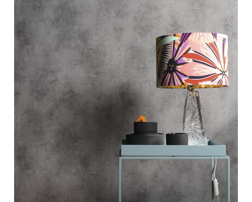 Szene mit floral gemusterter Lampe auf einem Beistelltisch vor einer grauen Wand