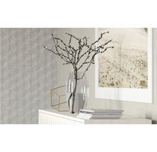 Dekorative Szene mit Vase, Ästen, geometrischer Dekoration und Bilderrahmen auf einem Sideboard vor einer gemusterten Tapete