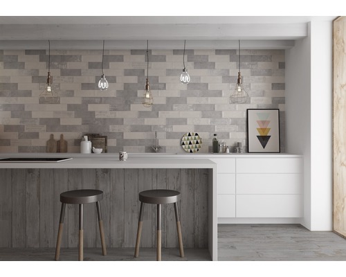 Moderne Küche mit grauen Wandfliesen in Backsteinoptik, Tresen mit Barhockern und weißen Schränken.