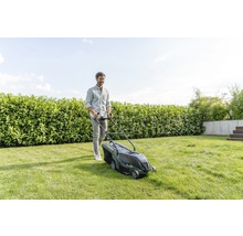 Frau bereitet Bosch Rasenmäher im Garten vor