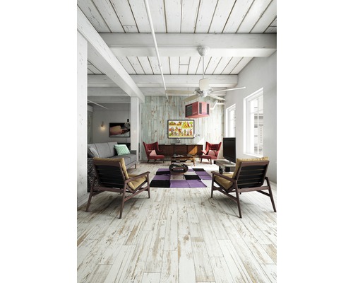 Salon lumineux avec plancher en bois, canapé, fauteuils et décoration