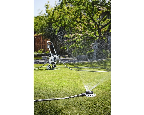 Gartenszene mit Rasensprenger und Schlauchwagen zur Bewässerung