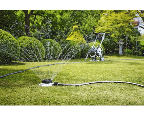 Rasensprenger bewässert Rasenfläche im Garten