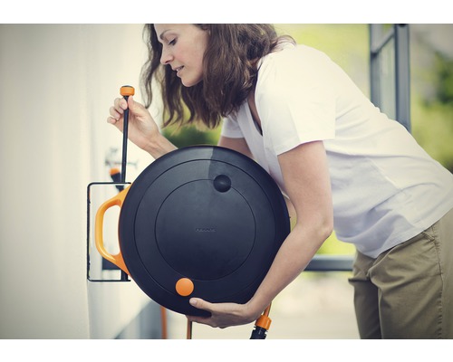 Frau benutzt Fiskars Schlauchbox zur Gartenbewässerung