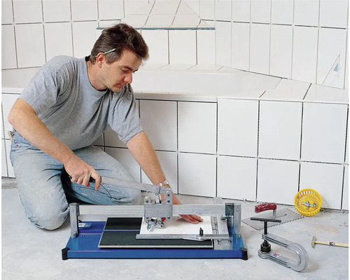 Handwerker schneidet Fliese mit Fliesenschneider im Badezimmer.