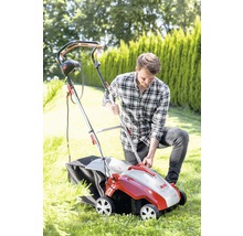 Un homme utilise un scarificateur dans le jardin. L''appareil est équipé d''un bac de ramassage.