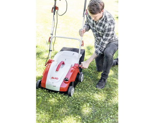 Un homme utilise un scarificateur de la marque AL-KO dans le jardin.