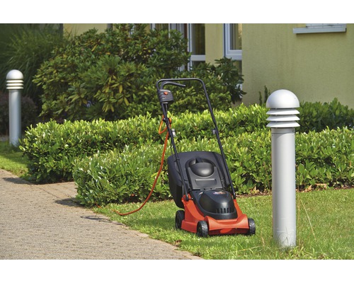 Tondeuse à gazon électrique sur une pelouse à côté d''un trottoir