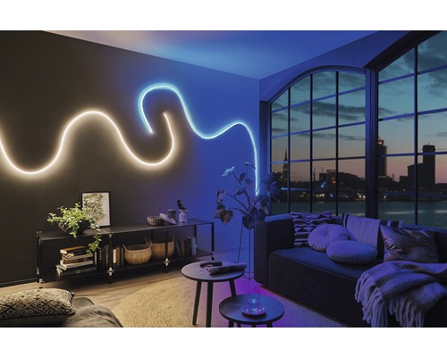Modernes Wohnzimmer mit flexiblen LED-Lichtleisten an der Wand, Regal und Sofa.