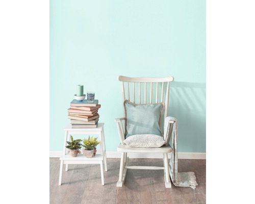 Scène avec fauteuil à bascule, table d''appoint, livres et décorations dans une pièce lumineuse.