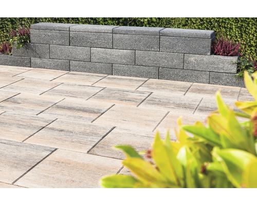 Graue Mauersteine und helle Pflastersteine im Aussenbereich.