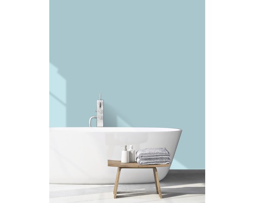 Salle de bain lumineuse avec baignoire îlot, robinetterie, serviettes et banc en bois