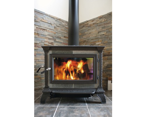 Poêle à bois avec feu et conduit de fumée devant un mur en pierre