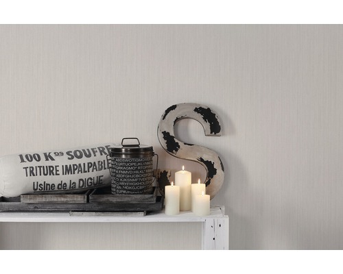 Arrangement décoratif avec coussin, boîte, bougies et un S sur une étagère