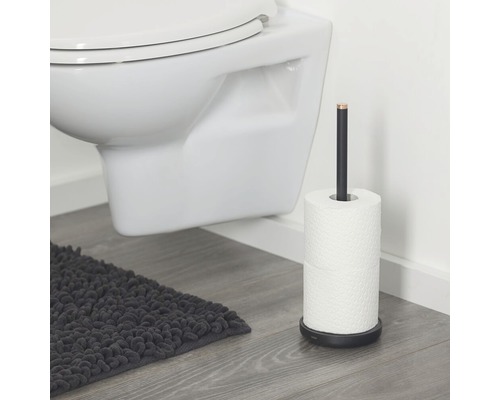 Freistehender Toilettenpapierhalter aus Metall neben einer Toilette und einem Badteppich
