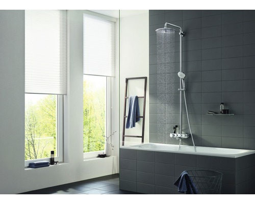 Helles Badezimmer mit Badewanne, Duschsystem und Fenster mit Plissees