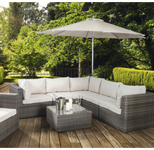 Scène de jardin avec ensemble de salon en rotin, table, parasol, seau à champagne, verres et bougies sur une terrasse en bois
