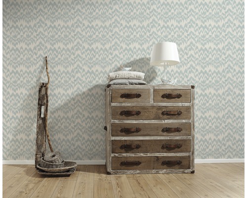 Dekoratives Zimmer mit gemusterter Tapete, Holzkommode und Tischlampe
